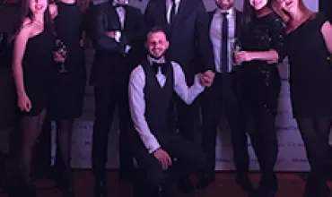 Group of nine people posing at a formal event.